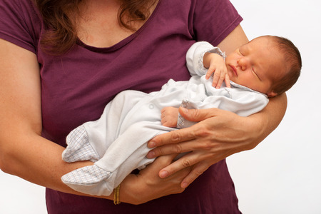Beautiful newborn babyboy sleeping peacefully in his mother armsの写真素材