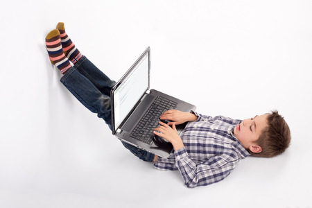 Lying boy using laptop.