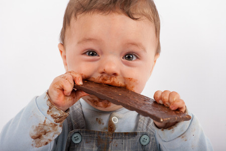 Happy baby eating chocolateの写真素材