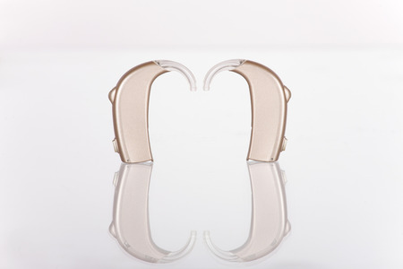 Two hearing aids left and right wreflecting glass surface