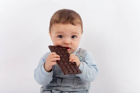 Beautiful baby boy eating a plate of chocolateの写真素材