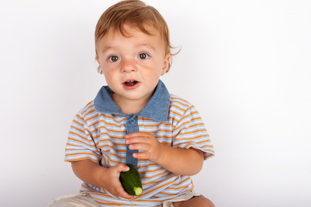 Adorable baby eating cucumberの写真素材