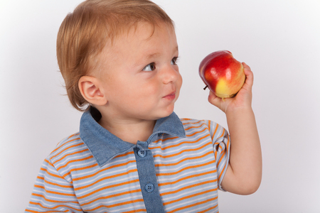 Adorable showing an apple which he eatingの写真素材
