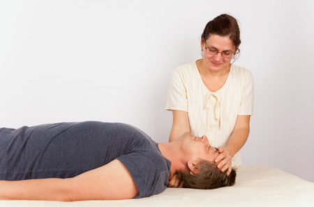 Middle aged man receives bowen treatment for his head. Bowen is a holistic system of healing.の写真素材