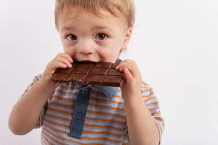 Adorable toddler boy eating a plate of chocolateの写真素材