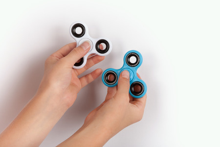 Hands with a white and a blue fidget spinnersの写真素材
