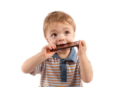 Portrait of a cute baby boy eating chocolate. Isolated on white background.の写真素材