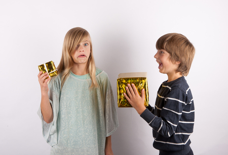 Big gift and small gift - siblings with with present boxes in different sizes. The owner of the bigger gift is laughing at the smaller's owner.の写真素材