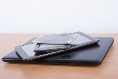 Stack of electronic gadgets on a table - notebook, tablet, ebook reader and a smatphoneの写真素材