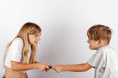 Siblings fighting for a smartphoneの写真素材