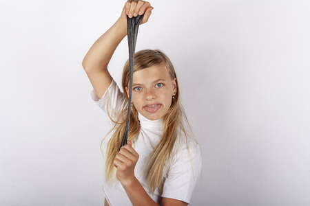 Funny girl stretching out her tongue playing with black slimeの写真素材