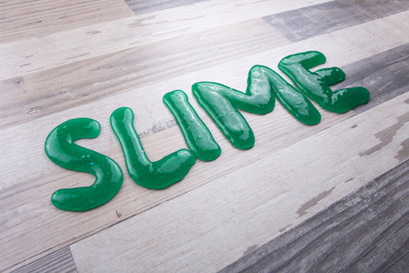 Slime text made from green slime on a wooden tableの写真素材