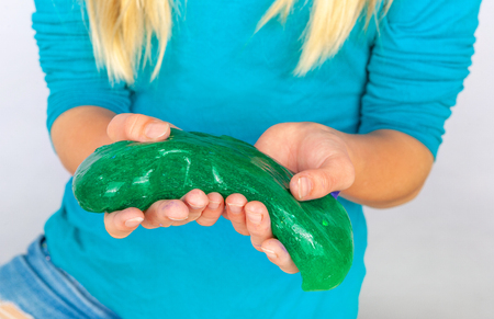 Young girl holding a green slime in her handsの写真素材