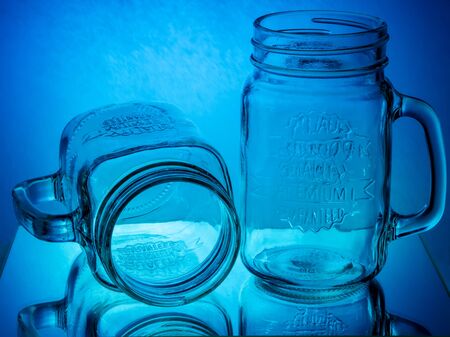Glass jar mugs on blue and red glowing backgroundの写真素材
