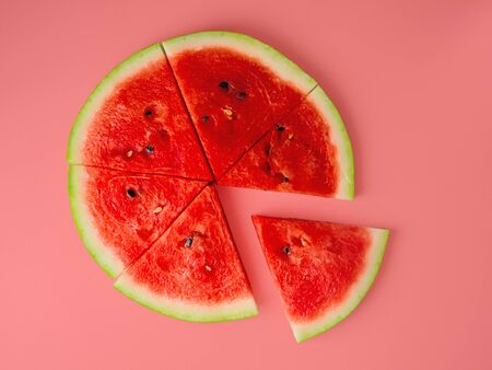 Slices of fresh red delicious watermelon are laid out in a circle on a colored background.の写真素材