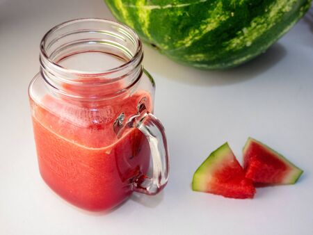 Fresh watermelon smoothie in a glass mug and slices of watermelon on a wooden backgroundの写真素材