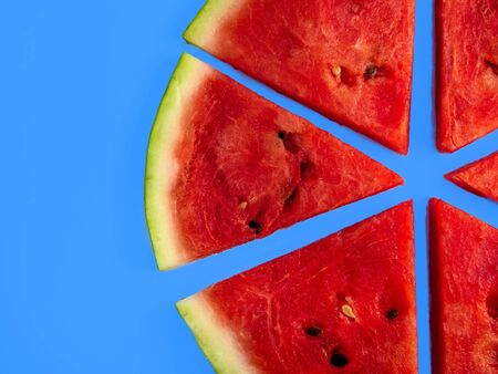 Slices of fresh red delicious watermelon are laid out in a circle on a colored background.の写真素材