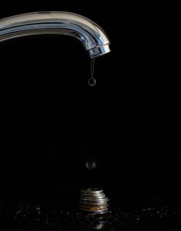 Water dripping from a faucet for moneyの写真素材