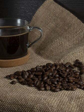 dark roasted coffee beans on burlap and a mug of freshly brewed natural coffee.の写真素材