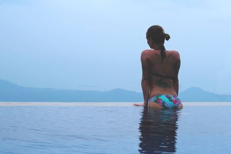 beautiful young european woman in the swimming pool near the ocean, spa, relaxing, tropical, vacation.の写真素材