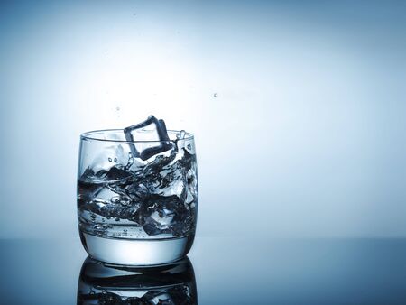 Ice cubes splashing into glass of water.の写真素材