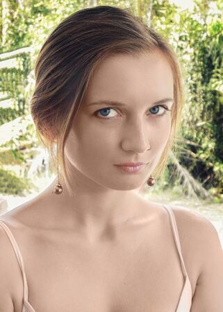 Beautiful young woman with clean perfect skin. Portrait of beauty model with natural nude make up and touching her face. Spa, skincare and wellness. Close up, blue background, copyspace.の写真素材
