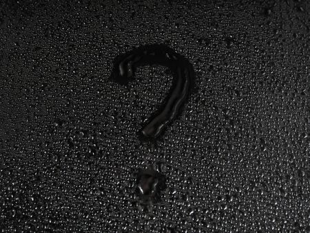 question mark written on a surface made of drops on a black background.の写真素材