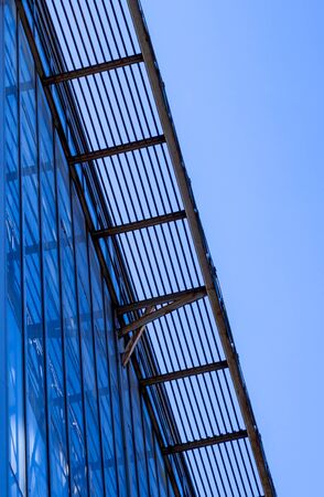 Building facade with blue sky. Glass wall in modern architecture.の写真素材