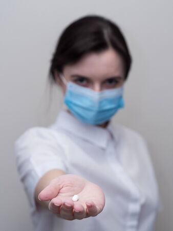 Doctor giving pills, woman in medical mask and gloves. The concept  the dose  drugs, vitamins, medical examination, , treatment  influenzaの写真素材