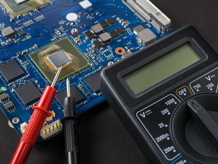 Multimeter test, electronic board of digital device with components. Troubleshoot electronic device. Computer and mobile device repair conceptの写真素材