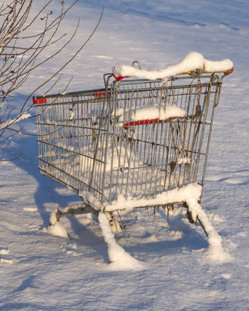 Shopping cart from the supermarket in the snow. The concept of closed stores, low demand, crisis, corontin. Consumer winter.の写真素材