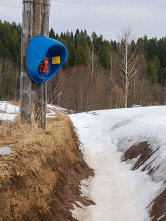 An old, forgotten, useless telephone in Siberia in the winter among the snow by the ditch.の写真素材