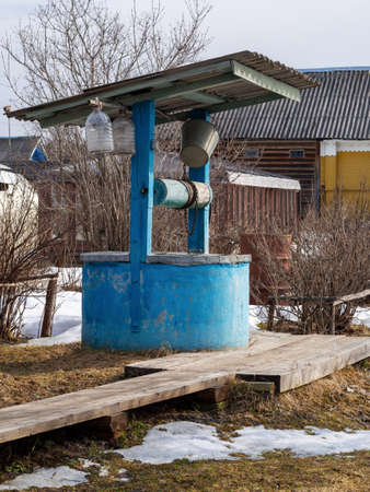 Village well under the roof with a metal chain on a cloudy autumn day, Russia.の写真素材