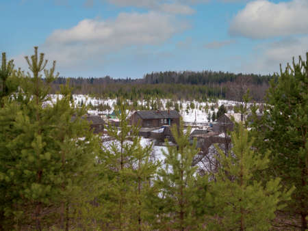 Village is in northern woods of Karelia, winter road with wooden house at evening. Russiaの写真素材
