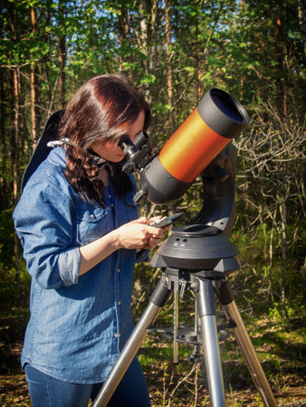Portrait of young woman looking through the telescope on the hilの写真素材