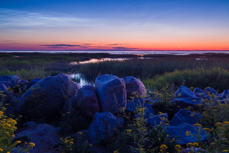 Pebble stones on the shore close up in the blurry sunset light in the distance background.の写真素材