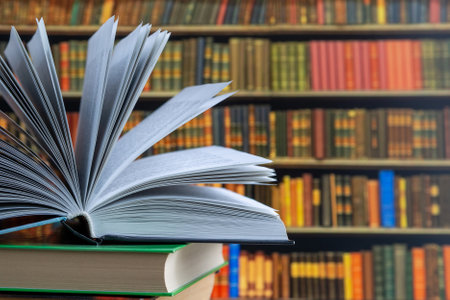 Book in library with old open textbook, stack piles of literature text archive on reading desk, and aisle of bookshelves in school study class room background for academic education learning conceptの写真素材