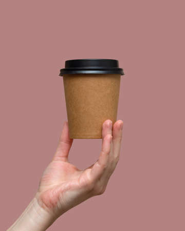 Woman hands hold paper cup on pink background. Copy space.の写真素材