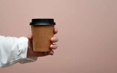 Woman hands hold paper cup on pink background. Copy space.の写真素材