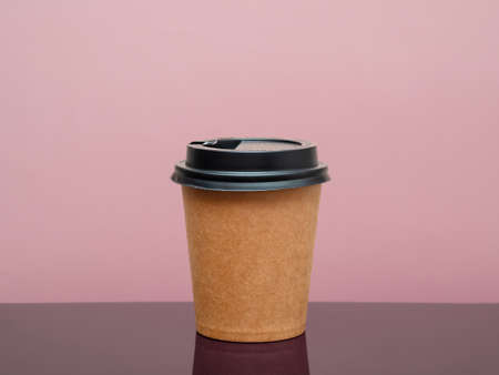 coffee to go in a disposable cup on the table and pink background. space for textの写真素材