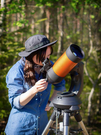 Portrait of young woman looking through the telescope on the hilの写真素材