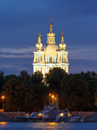 View of the Smolny Cathedral and the Russian Navy warship from the side of the Neva at night on a cloudy summer day. Russia, Saint-Petersburg. Day of the Navy.のeditorial素材
