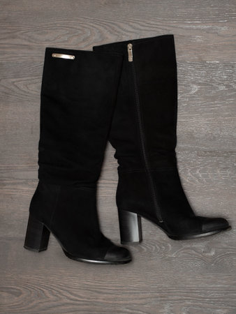 Women's black boots on a wooden background.の写真素材