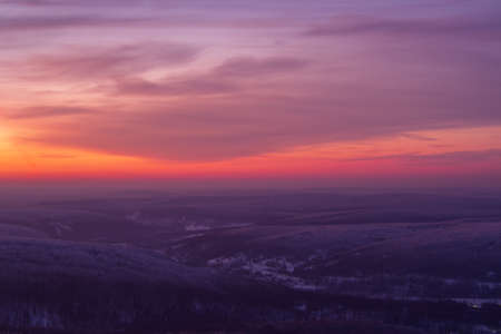 Epic red sunset over the rocks and stones of Ural mountains covered with snowy pinesの写真素材