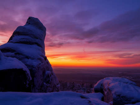 Epic red sunset over the rocks and stones of Ural mountains covered with snowy pinesの写真素材