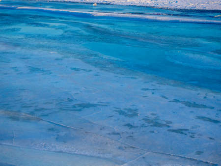 Network of cracks in thick solid layer of ice of a frozen riverの写真素材