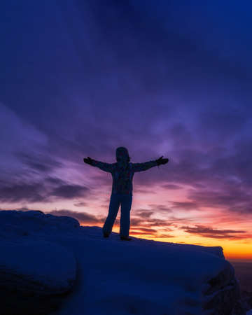 Silhouette of a man with hands raised in the beautiful sunsetの写真素材