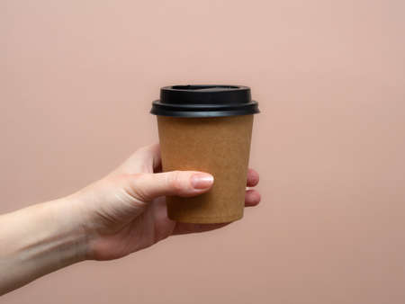 Woman hands hold paper cup on pink background. copyspace.の写真素材