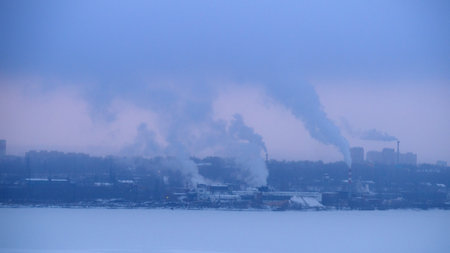 Chimneys smoke in winter against the background of the city and the sky.の写真素材