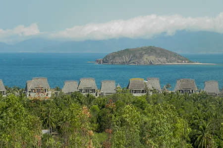 thatched-roof bungalows in the jungas against the backdrop of the sea and mountainsの写真素材